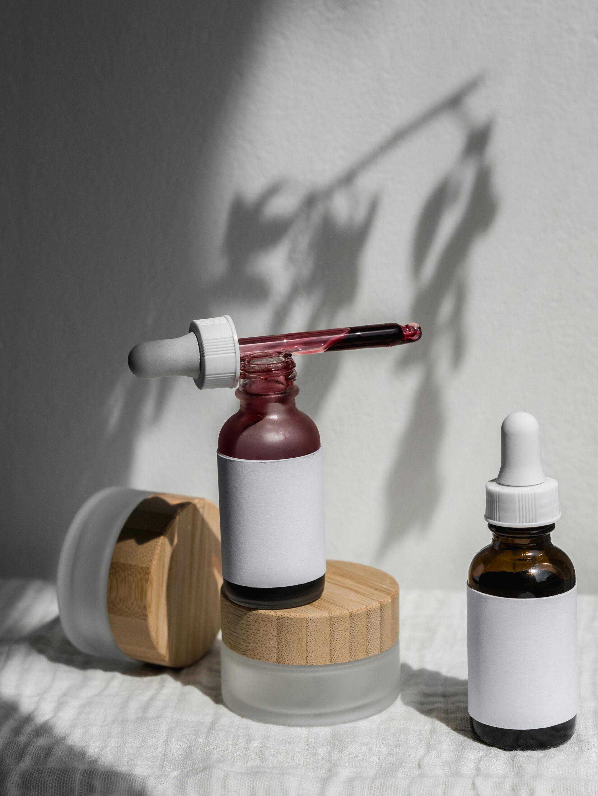 Minimalist skincare product display with natural light and artistic shadows.